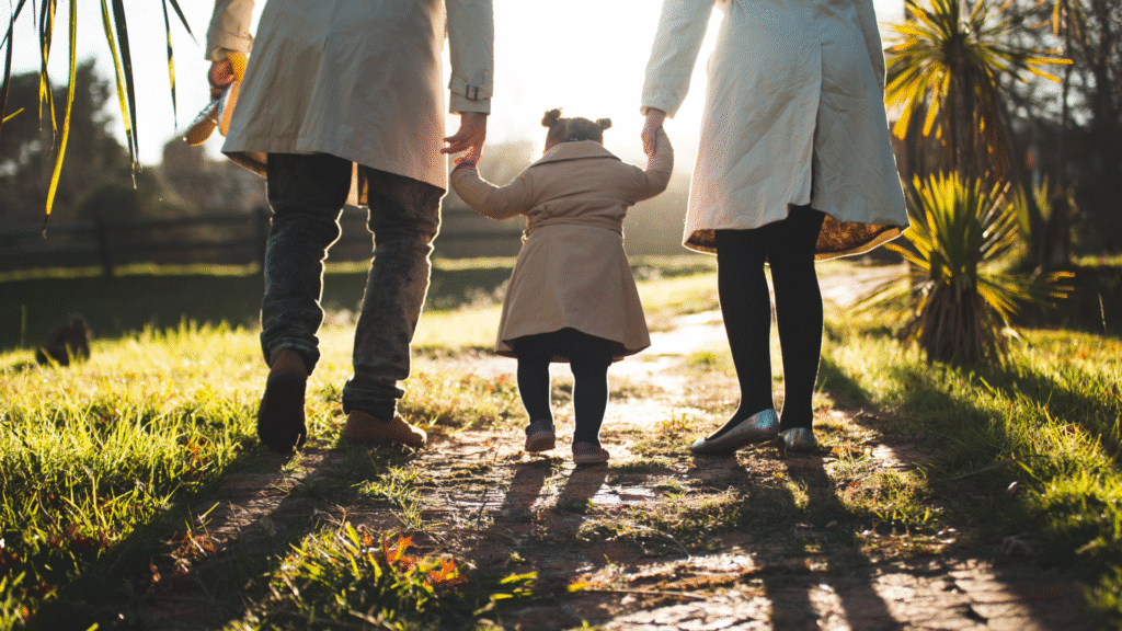 image of two parents holding and walking with a child.